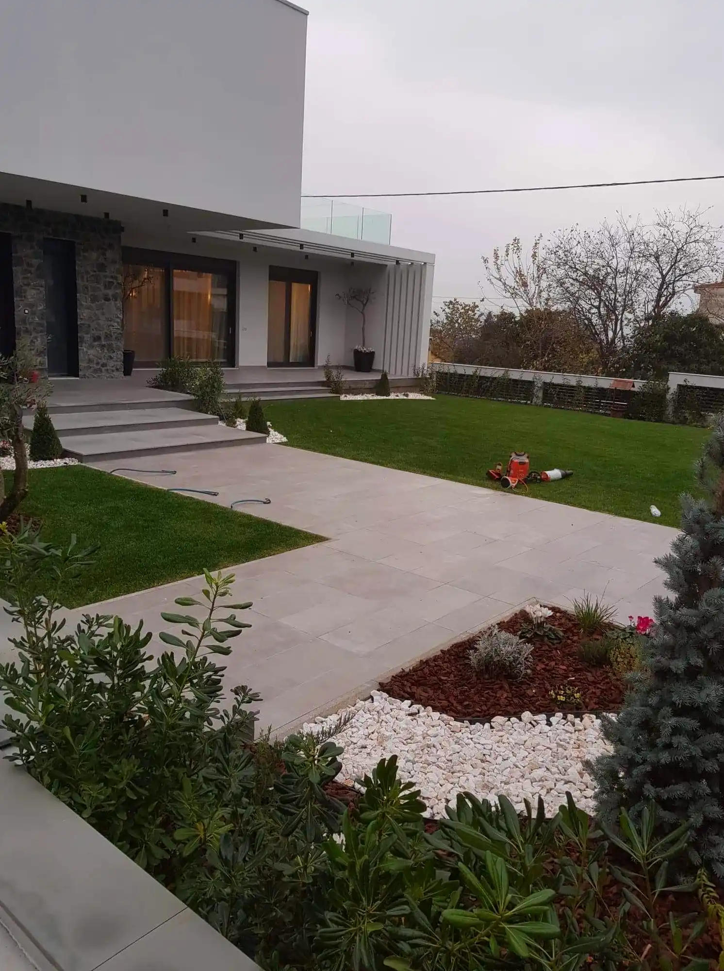 Modern house with lawn, paving and white-pebble beds
