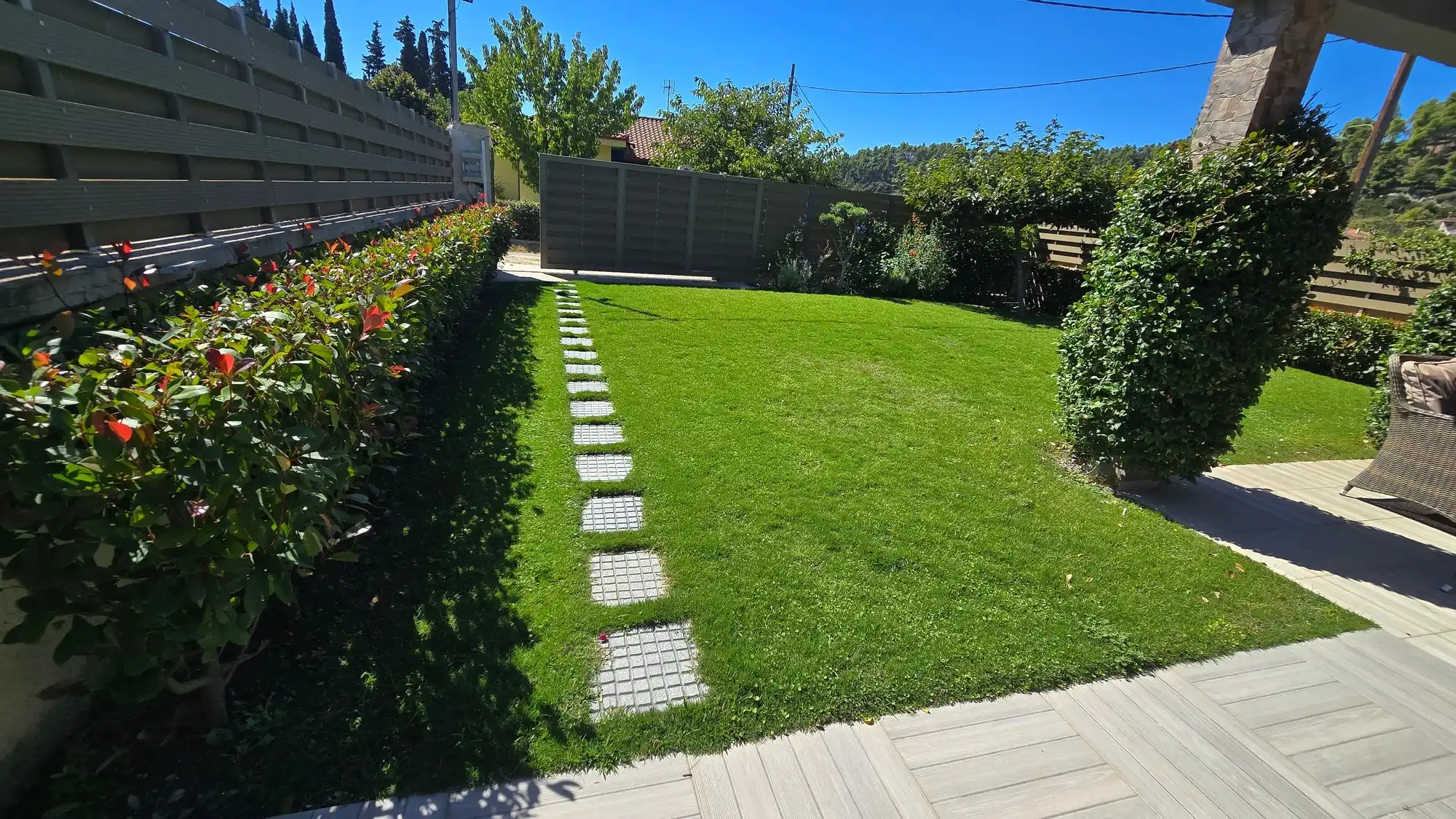 Well-kept lawn with stepping stones and a trimmed hedge